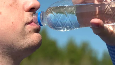 Young man drinks water from a transparent plastic bottle Stock Footage 155471550