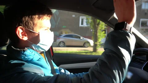 Young Man Driving and Pulling Down Sun Visor Wearing Surgical Face Mask, COVID19 Stockbeeldmateriaal 131048056