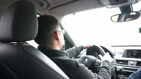 A young man driving a car and returning a greeting by waving with his hands on a Stock Footage 155779637