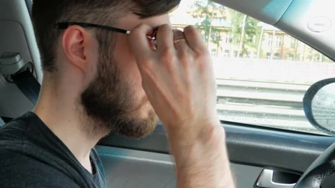 A young man is driving in a car. Putting on sunglasses Stock Footage 130470705