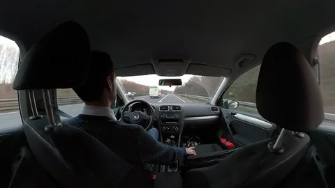 Young man driving a car, view from back seat through windshield Stock Footage 103793228