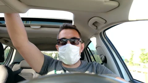 Young man driving car wearing medical mask during coronavirus Stock Footage 134054976