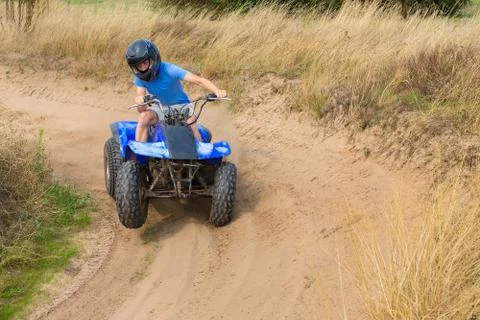 Young man driving quad through curve Stock Photos