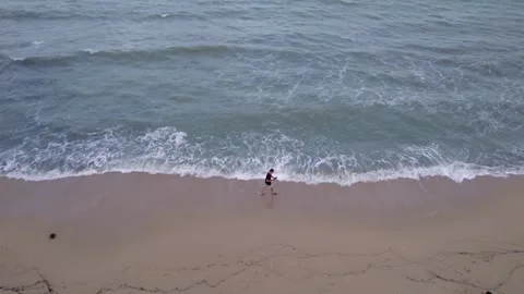 Young man with drone controller tracks himself on beach, then flies up, cloudy Stock Footage 275848066