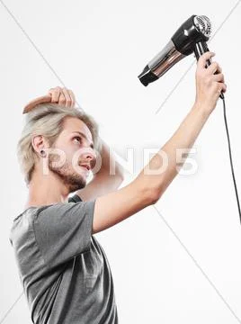 Young man drying hair with hairdryer Stock Photos