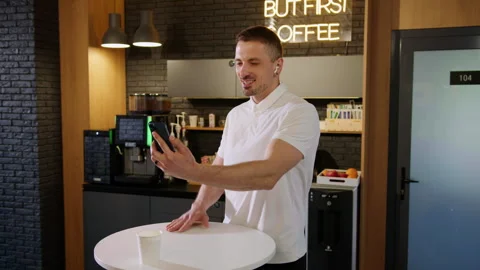 A young man during a video call on the phone in an office cafe Stock Footage 246052938