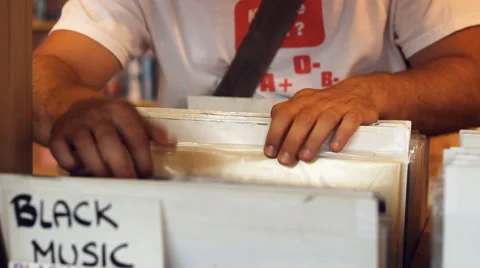 A Young man eagerly browses through a selection of black music vintage records Stockbeeldmateriaal 40634292