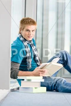 Young man with earbuds and books Stock Photos