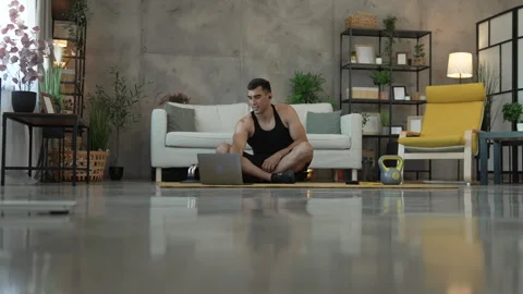 Young man with earphones take a break from training and use laptop Stock Footage 278332953