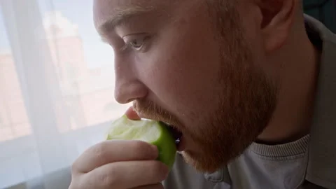 Young Man Eating Green Apple while Working on Laptop at Home Stock Footage 315862276