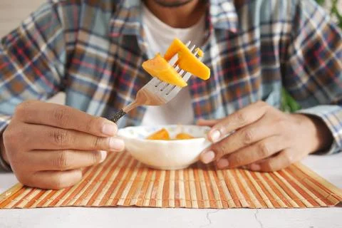 Young man eating mango while sited Stock Photos