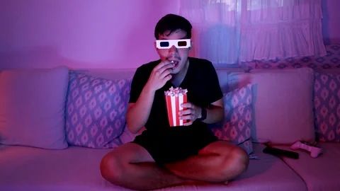 Young man eating popcorn with 3D glasses Stock Footage 289735352