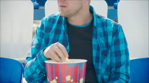 Young man eating popcorn at the stadium Stock Footage 63840456