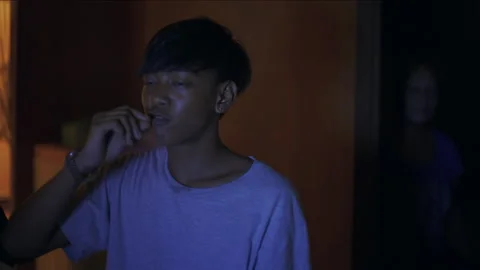 Young man eating a snack while watching a movie at night 库存影片 334374314