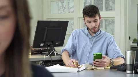Young man eating while working in an office 動画素材 83396200