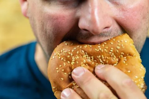 Young man eats delicious appetizing burger. Stock-Fotos