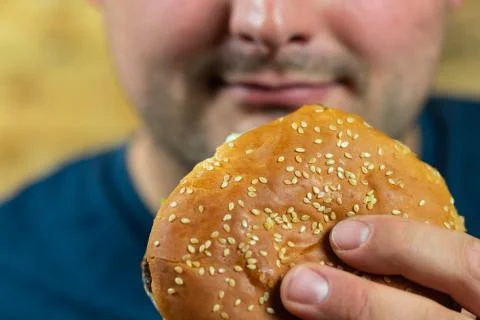 Young man eats delicious appetizing burger. Stock Photos