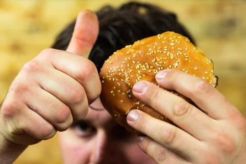 Young man eats delicious appetizing burger. Stock Photos