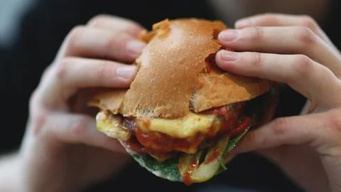 Young man eats meat burger with pleasure, bites burger with his mouth, man Foto stock