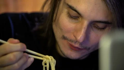 The young man eats with pleasure Chinese noodles sticks. Vídeos de archivo 87047145