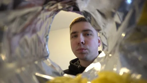 Young man eats potato chips while sitting at home. View of the man from the bag Stock Footage 236475805