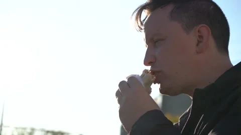 A young man eats shawarma on the go. Stock Footage 143843106