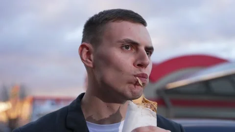 A young man eats shawarma on the street, slow motion Stock Footage 224661475