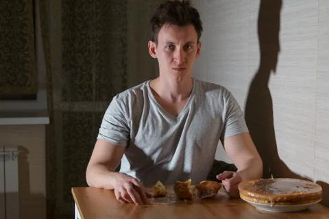 Young man eats sweets in the kitchen at night Foto stock