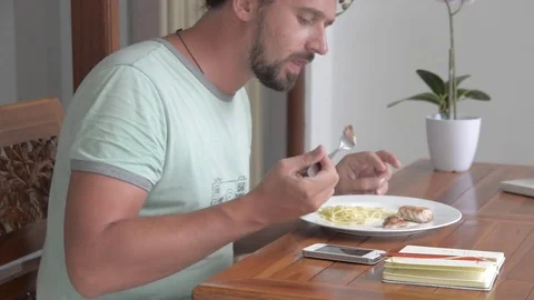 A young man eats a tuna steak with spaghetti. Stock Footage 84788464