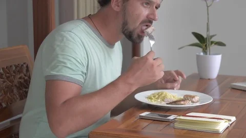 A young man eats a tuna steak with spaghetti. Stock Footage