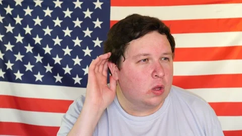 Young man eavesdropping on the background of an USA flag Stock Footage 107080044