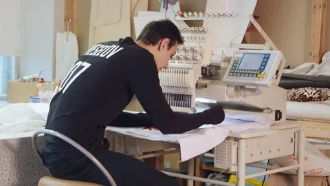 Young man is embroidering pattern on computerized machine Stock Footage 89344558