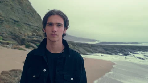 Young man  on the empty ocean beach, on the cloudy rainy weather. Confident a Stock Footage 197335831