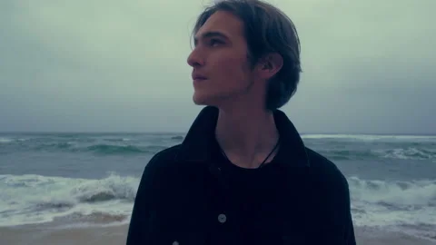 Young man  on the empty ocean beach, on the cloudy rainy weather. Sexy guy is Stock Footage 197336121