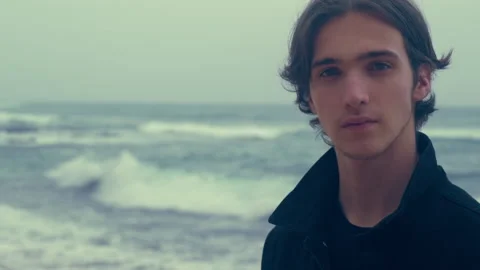 Young man  on the empty ocean beach, on the cloudy rainy weather. Confident.. Stock Footage 264927841