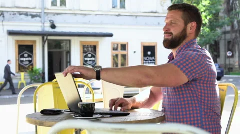 Young man ends typing on laptop and relaxes in cafe, slider shot right Stock Footage 67632428