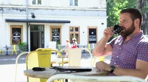Young man ends typing on laptop, drinks coffee and relaxes in cafe, slider shot. 库存影片 67632720