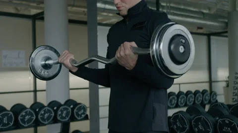 Young man is engaged in crossfit, doing biceps exercise, warming up, in the gym. Stock Footage 130420109