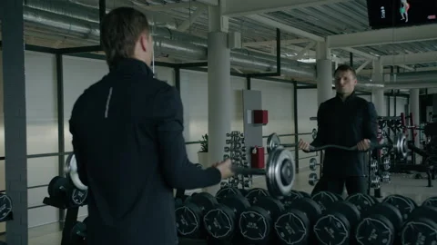 Young man is engaged in crossfit, doing biceps exercise, warming up, in the gym. Stock Footage 130420267