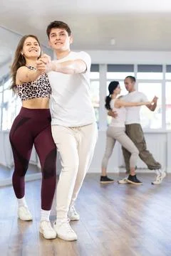 Young man engaged in dance hall with female partner and dances Latin rumba Stock Photos