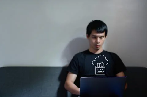 Young Man Engaged in Data Transfer with Laptop on Couch Stockfoto's