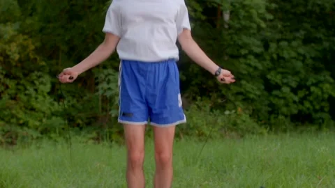 Young man engaged in jump rope activity amidst green surroundings Stock Footage 321028037