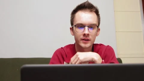 Young man engaged in online video meeting using laptop at home Stock Footage 301691153