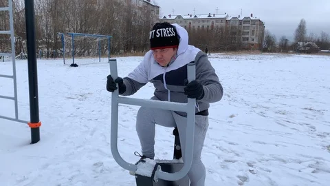 A young man is engaged in an outdoor exercise bike in winter Vídeo Stock 119487580