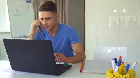 Young man engaged in a phone conversation at his modern office desk Stock Footage 311990262