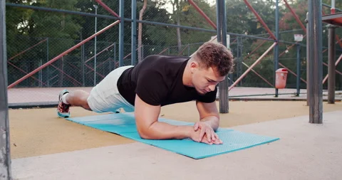 A Young Man Engaged in the Plank Exercise Outdoors to Enhance His Overall Stock Footage 318073334
