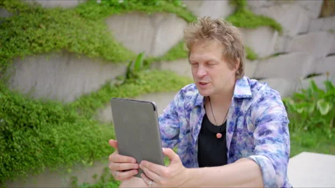 A young man is engaged with technology while enjoying his time outdoors in a Stock Footage 283293886
