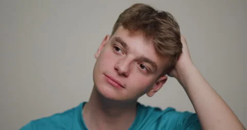 Young man engaged in a thoughtful moment while sitting casually in a simple Stock Footage 346651697