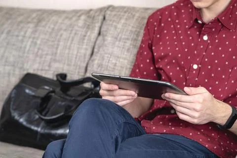 A Young Man Engaged in Using a Tablet While in a Relaxed and Casual Setting of Stock Photos