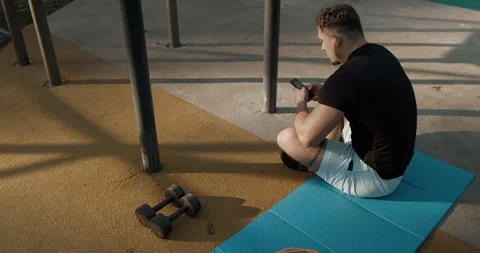 A Young Man Engaged in a Workout Session at an Outdoor Gym Utilizing Dumbbells Stock Footage 317837371